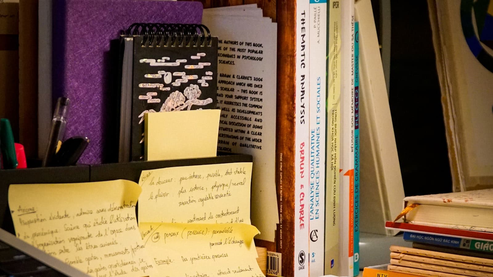 A study desk stacked with grammar and exam books and handwritten vocabulary notes